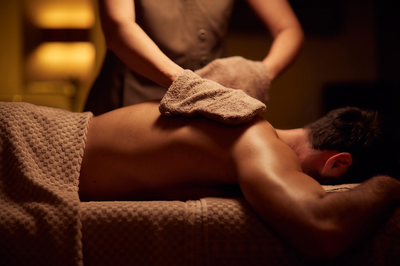 Spa therapist giving a man a relaxing back massage treatment.